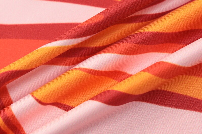 Printed garment fabric with wavy multicolor stripes in orange, red, pink, and white