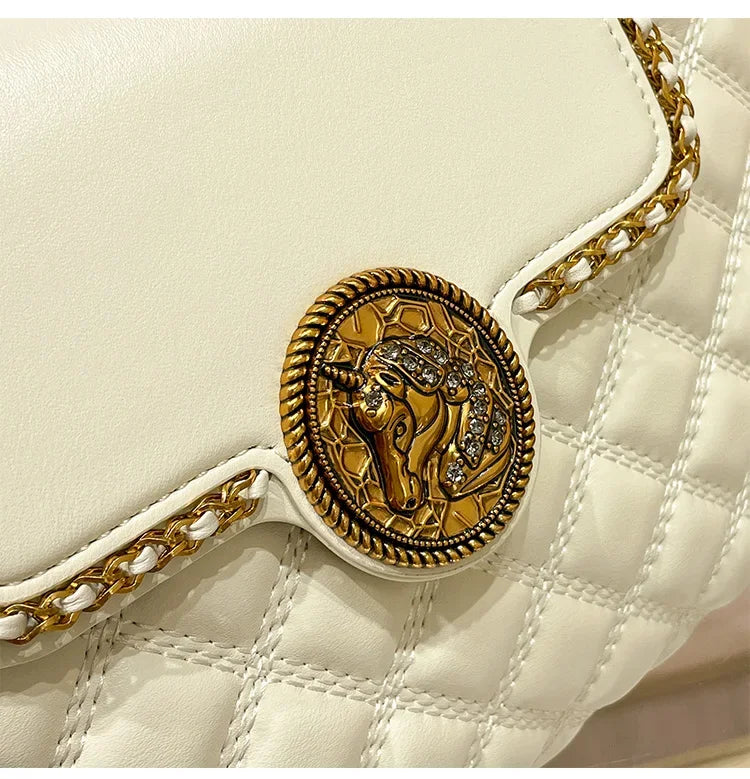 White quilted shoulder bag close-up with round lion-medallion clasp and gold chain