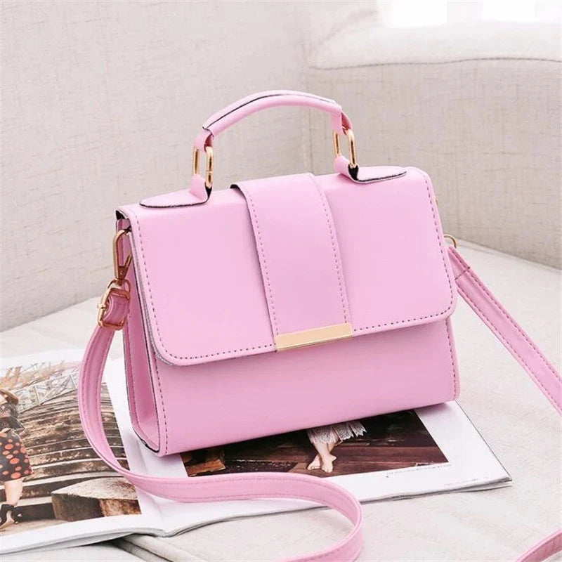 Small pink flap bag with top handle, shoulder strap, and gold-tone buckle hardware