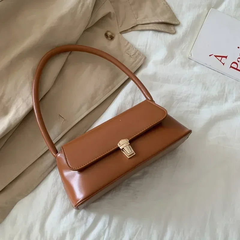 Caramel brown top-handle handbag with front clasp and curved handle
