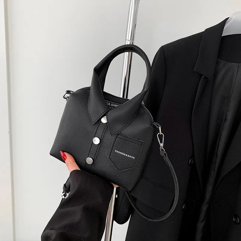 Black mini handbag with top handle, wrist strap, button front, and side metal rings