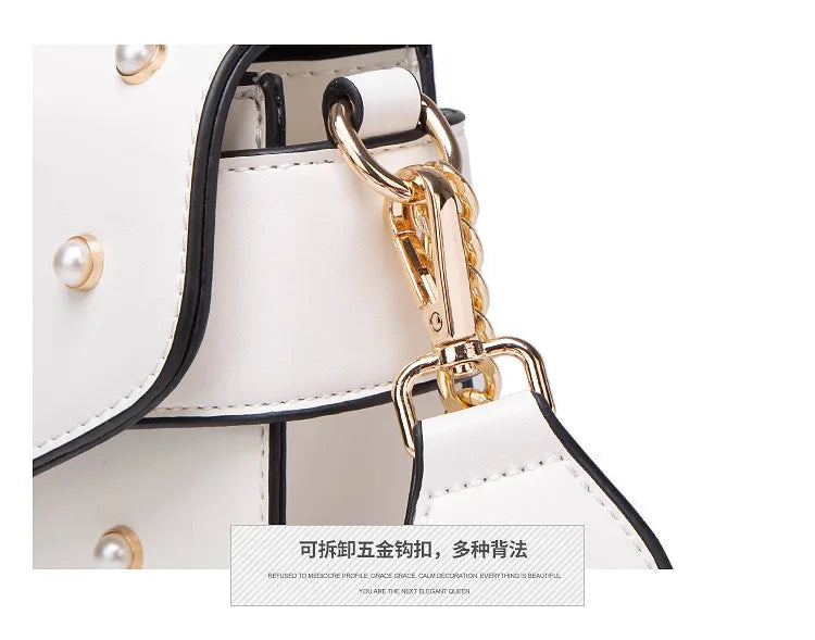 Close-up of white flap handbag hardware with gold chain and black-edged strap.