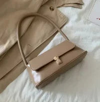 Small beige handbag with top handle, front flap, and clasp hardware
