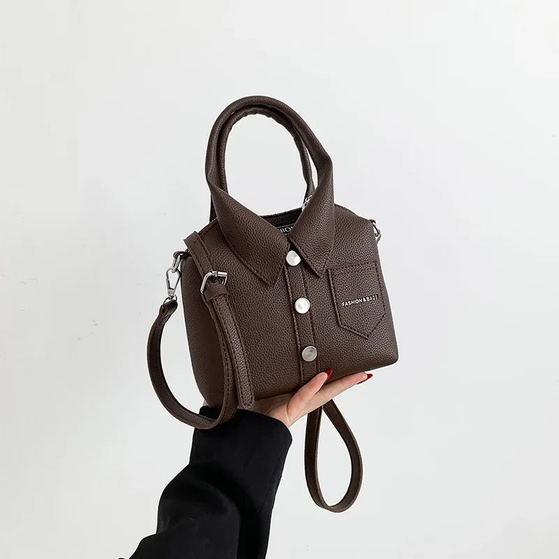 Brown mini handbag with top handle, wrist strap, front flap pocket, and metal rings