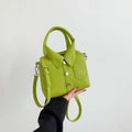 Green mini handbag with top handle and shoulder strap, button front, and patch pocket