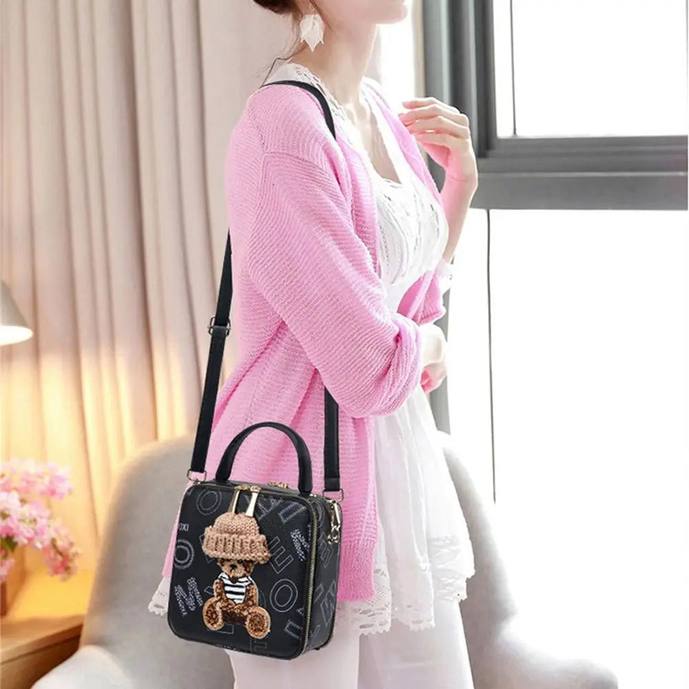 Black mini crossbody bag with teddy patch and crochet hat, worn with pink cardigan