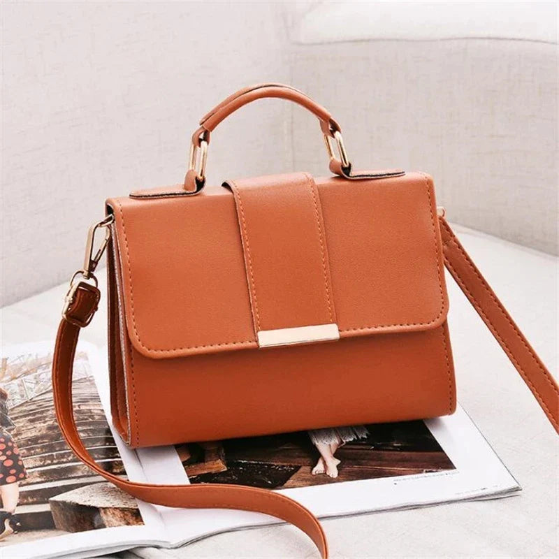 Small orange flap bag with top handle, shoulder strap, and gold-tone buckle hardware