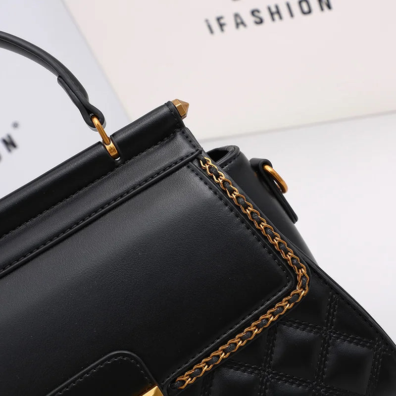 Black handbag corner detail with gold chain trim and metal hardware