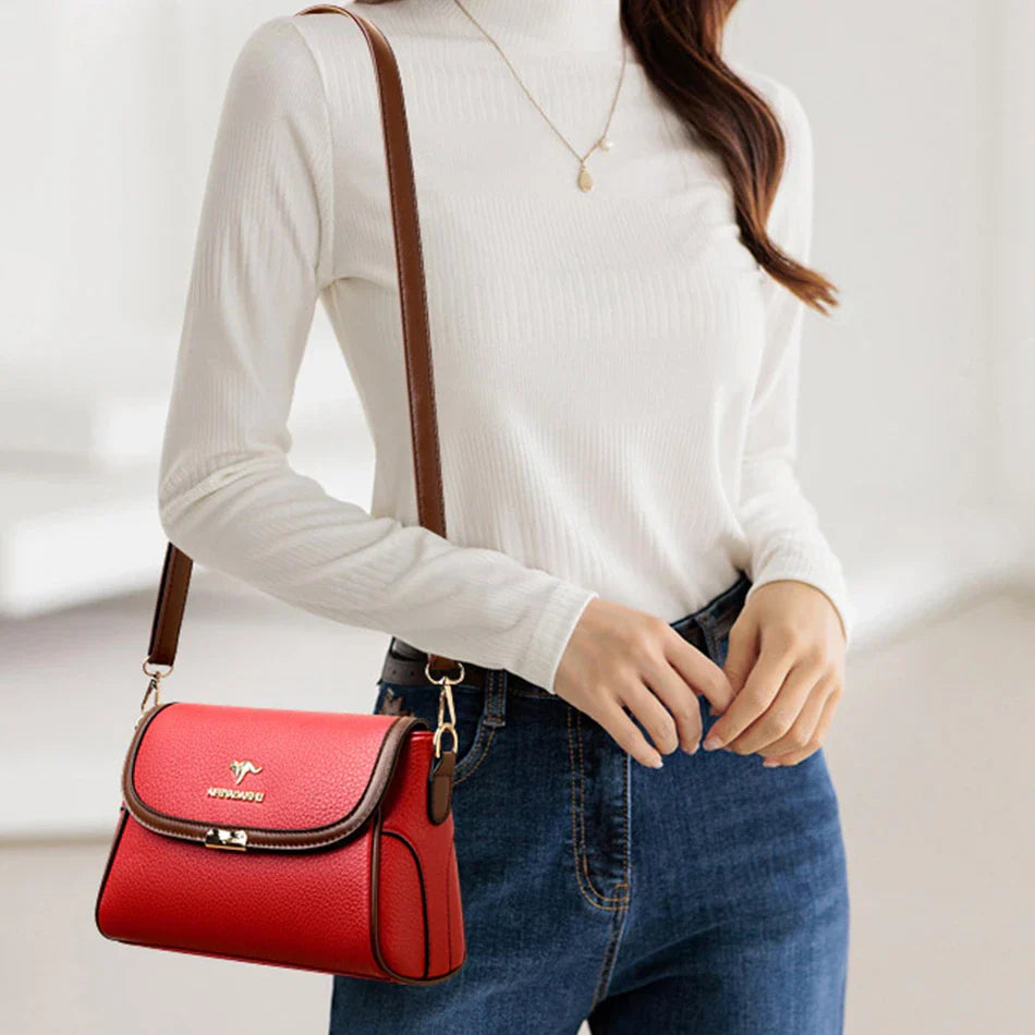 Red leather crossbody bag with front flap, gold-tone hardware, and adjustable shoulder strap
