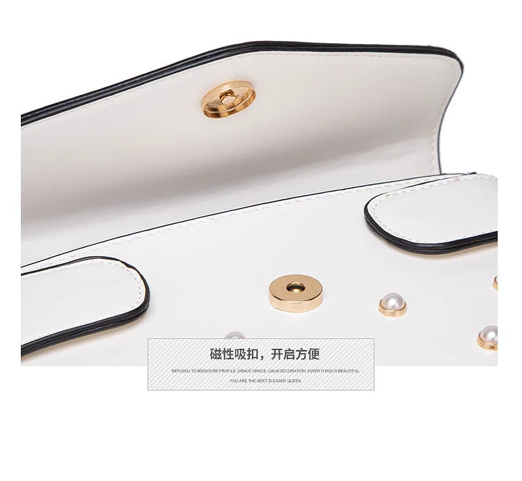 Close-up of white flap handbag snap button and pearl stud on leather surface.