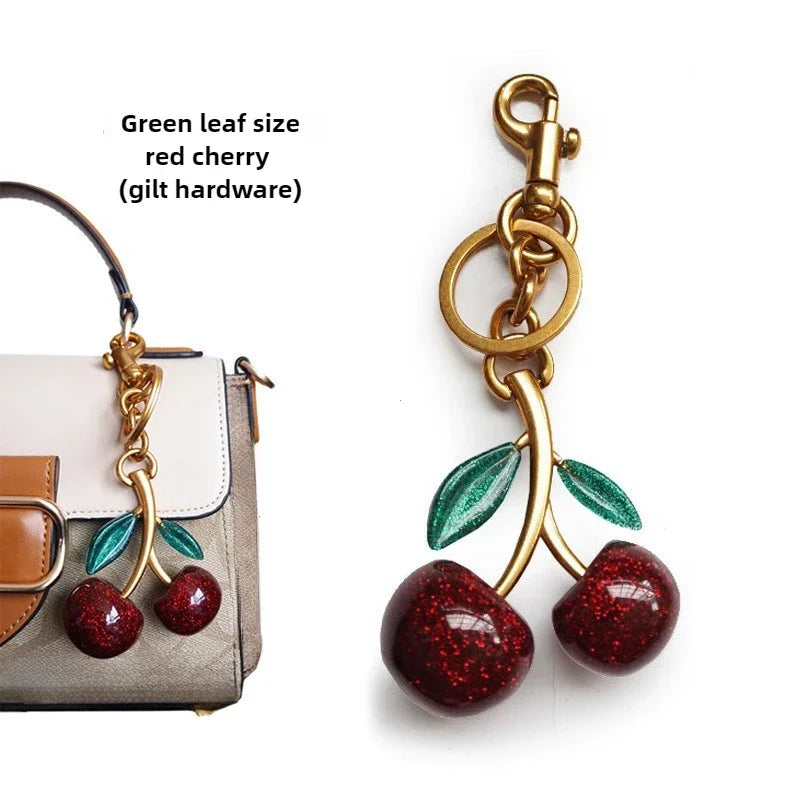 Gold keychain charm with cherries, leaf accents, and a hanging ring clip