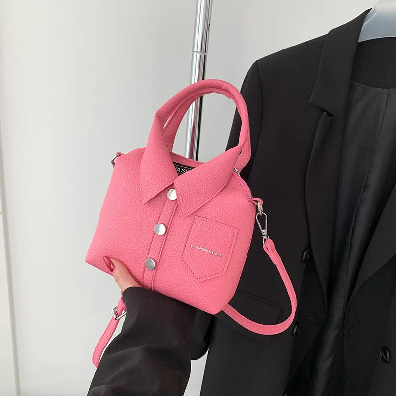 Pink mini handbag with top handle, wrist strap, button front, and side metal rings