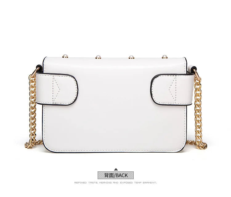 White flap handbag with two pocket-like panels and gold chain strap.