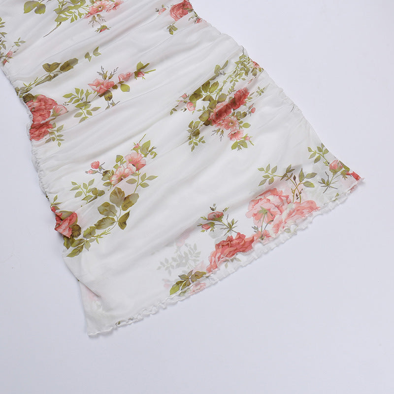 Floral slip dress in white with pink roses and green leaves, gathered ruffle hem