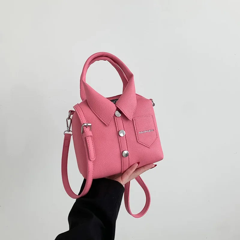 Pink faux-leather handbag with top handle, wrist strap, front pocket and metal snap