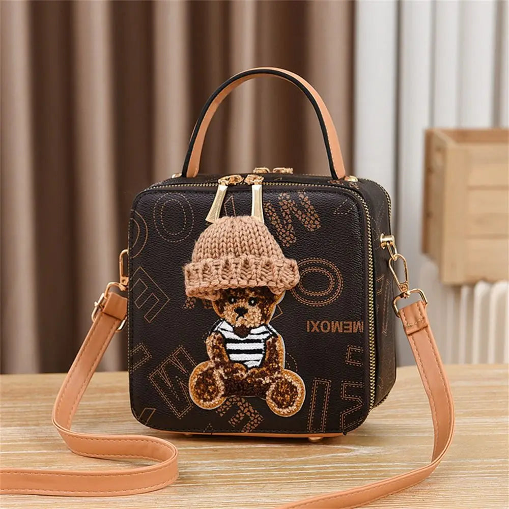 Dark brown patterned crossbody bag with teddy bear patch and knit hat, tan shoulder strap