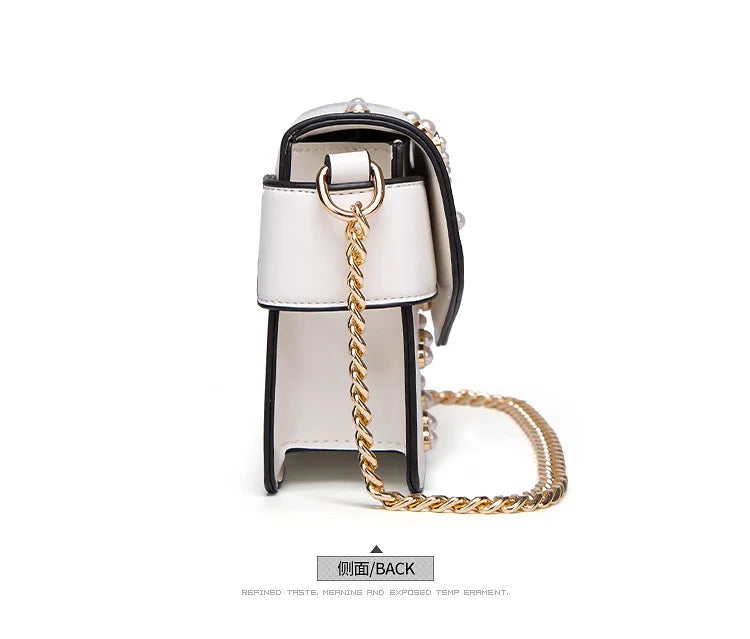 White flap handbag back with gold chain strap and black trim around the opening.