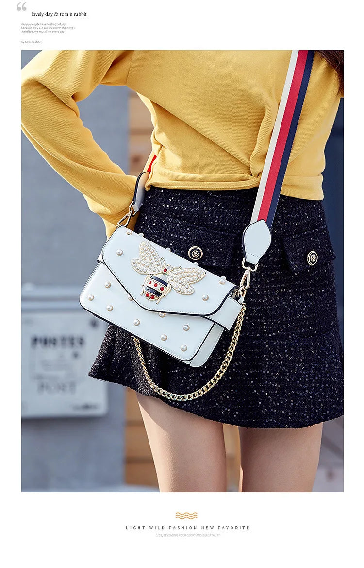 White flap crossbody bag with striped web strap and gold chain shoulder