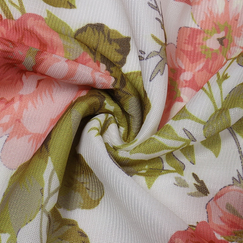 Floral print fabric close-up with pink blooms, green leaves, and white base