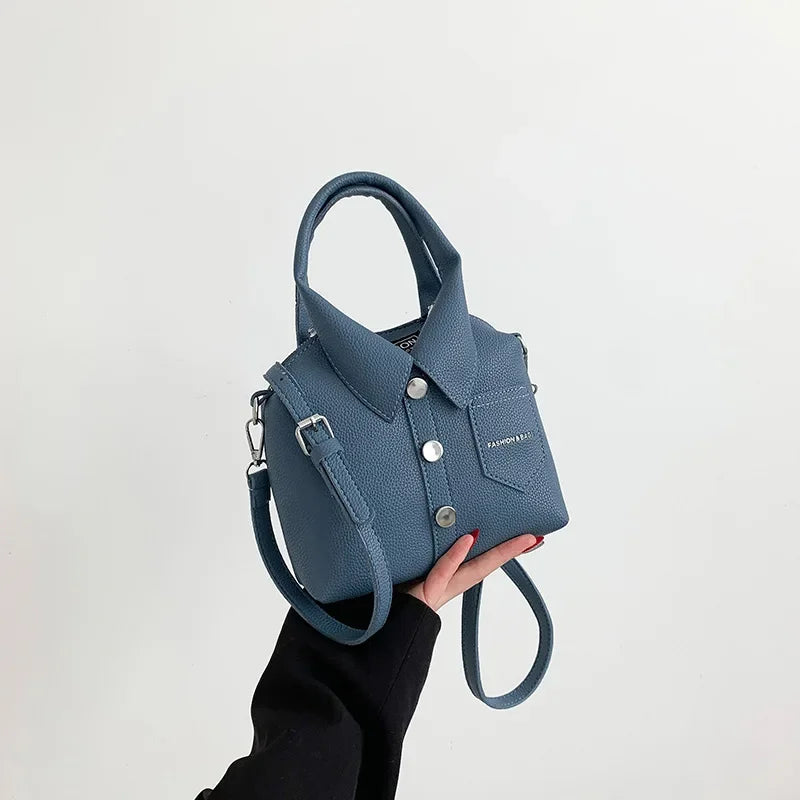 Blue mini handbag with top handle, wrist strap, button front, and front patch pocket