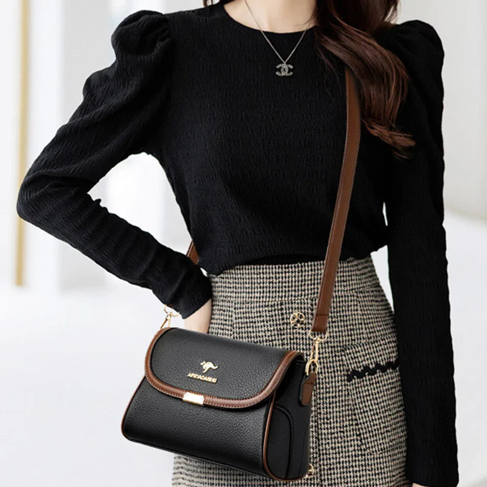 Black leather crossbody bag worn on model with front flap and adjustable strap