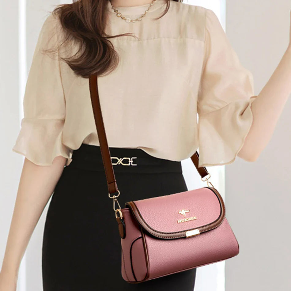 Pink leather crossbody bag worn on model with chain shoulder strap and front flap