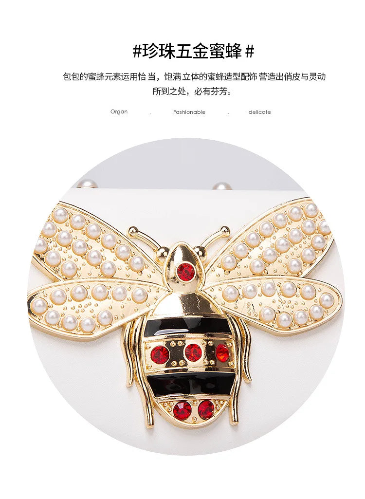 Pearl bee bow clasp detail on white flap bag with red accents and gold hardware