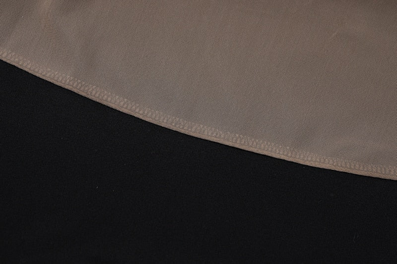 Black sheer fabric panel with fine knit texture, close-up seam edge