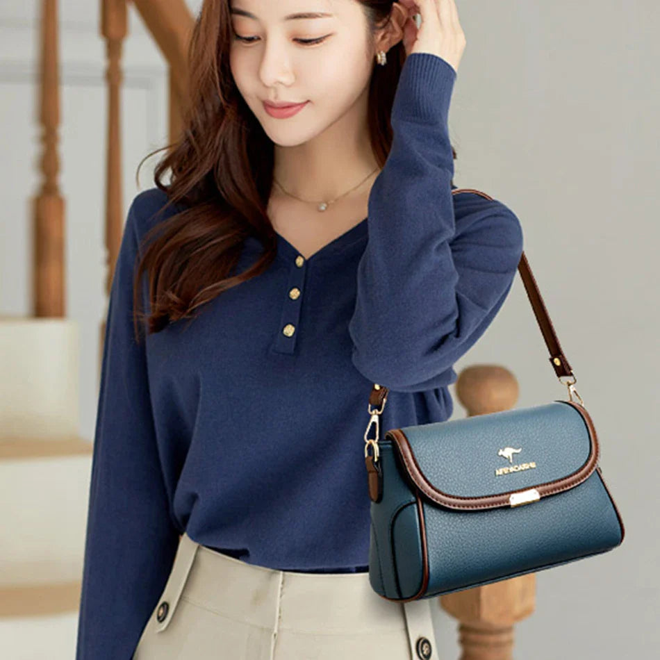 Blue leather crossbody bag worn on model with front flap and adjustable shoulder strap