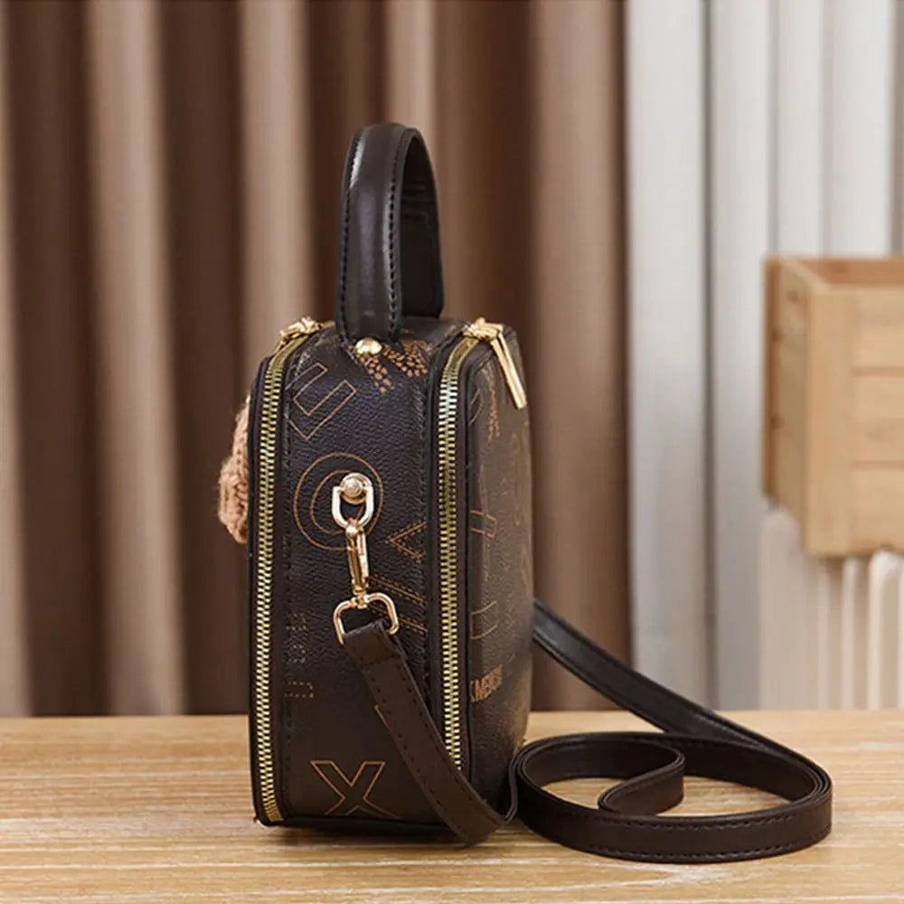 Black mini crossbody bag with front zipper, gold hardware, adjustable shoulder strap