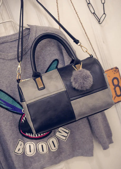 Color-block duffel bag, gray and dark navy, with pom-pom charm and crossbody strap