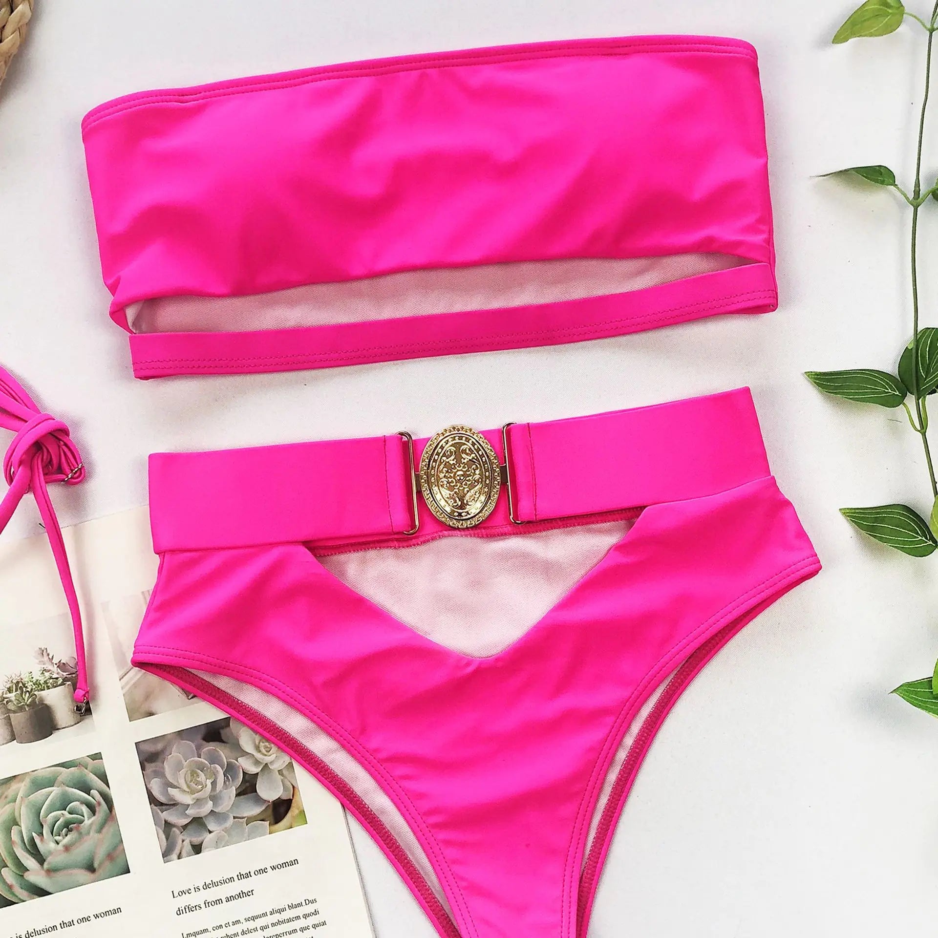 Hot pink bikini set flat lay: strapless bandeau top and high-waisted bottoms with gold clasp