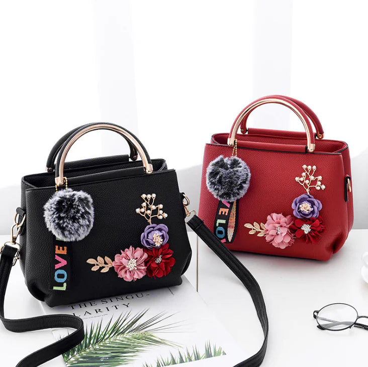 Two leather shoulder bags, black and red, with pompom, floral applique and LOVE strap