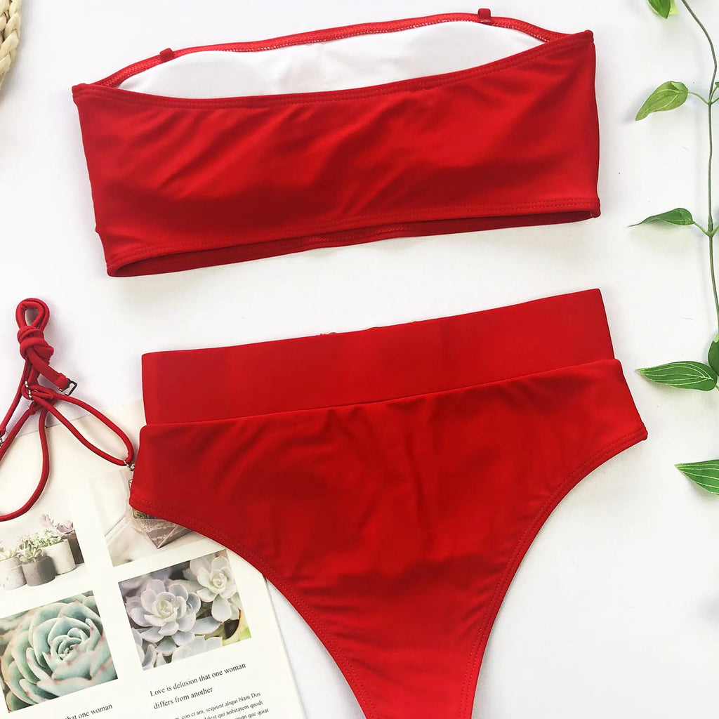 Red bandeau bikini top and high-waist bikini bottoms set, flat lay.